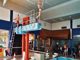 Jungs, die im Hallenbad vom Sprungtum springen