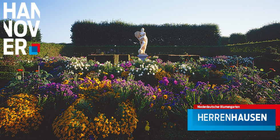 Viele bunten Blumen im Niederdeutschen Blumengarten im Großen Garten Herrenhausen, in der Mitte steht eine steinerne Figur, im Bildhintergrund wird der Garten von Hecken umrahmt