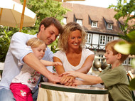 Familie an einem Tisch unter einem Sonnenschirm