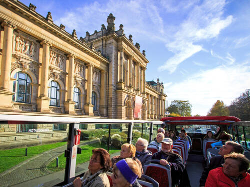 Ein Bus fährt an einem großen Gebäude vorbei.