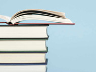 Fünf Bücher, die etwa die gleiche Dicke haben, aufeinandergestapelt. Das Buch ganz oben ist aufgeklappt.
