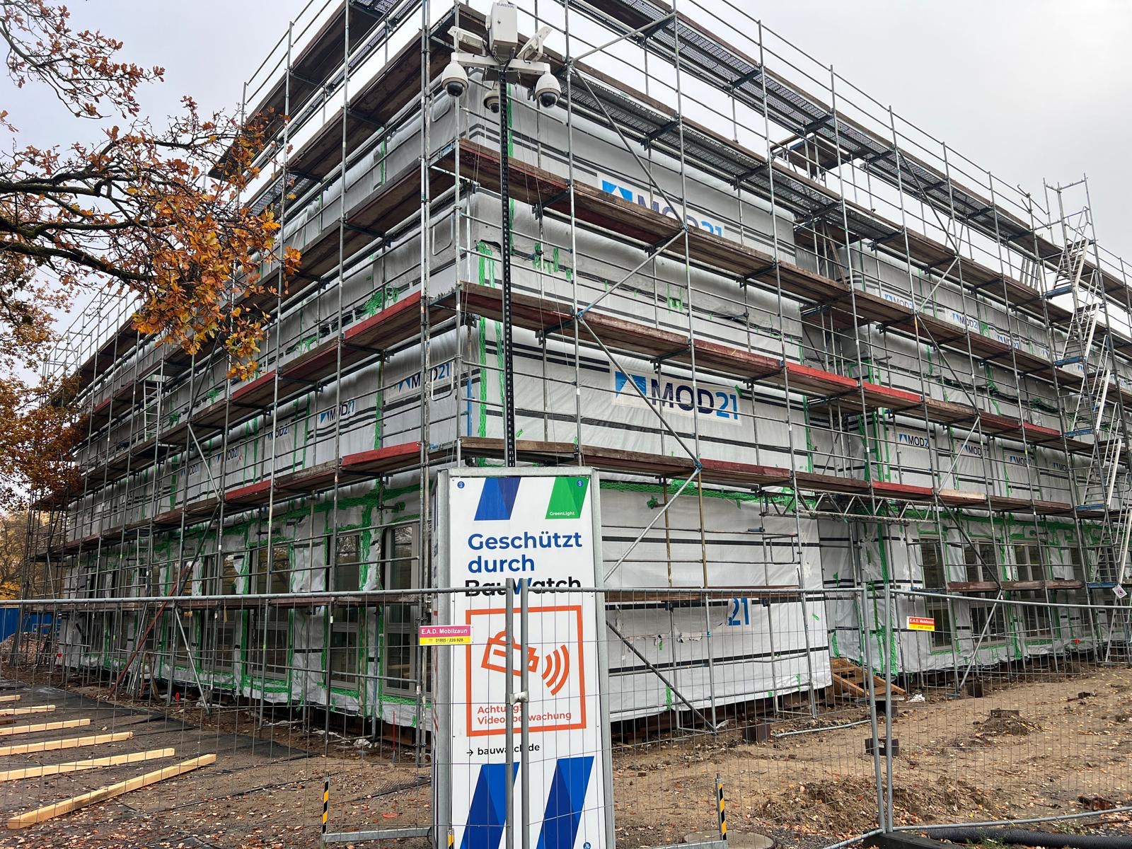 Ein Bauger&uuml;st um den Rohbau eines etwa dreigeschossigen hellen Geb&auml;udes.