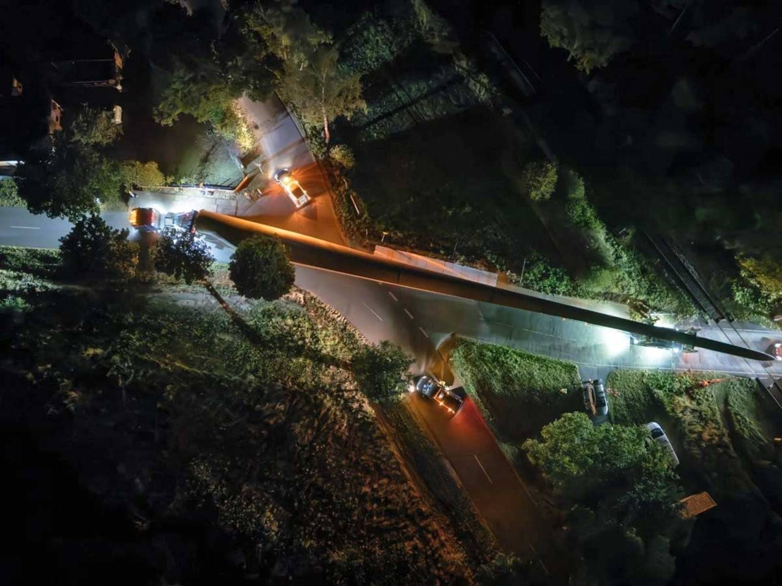 Nächtlicher Transport eines Rotorblattes für ein Windrad, aus der Vogelperspektive aufgenommen.