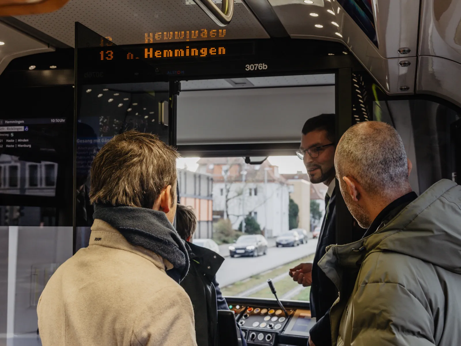 2 Personen, denen etwas mit Blick aus der Fahrerkabine einer Stadtbahn erkl&auml;rt wird.
