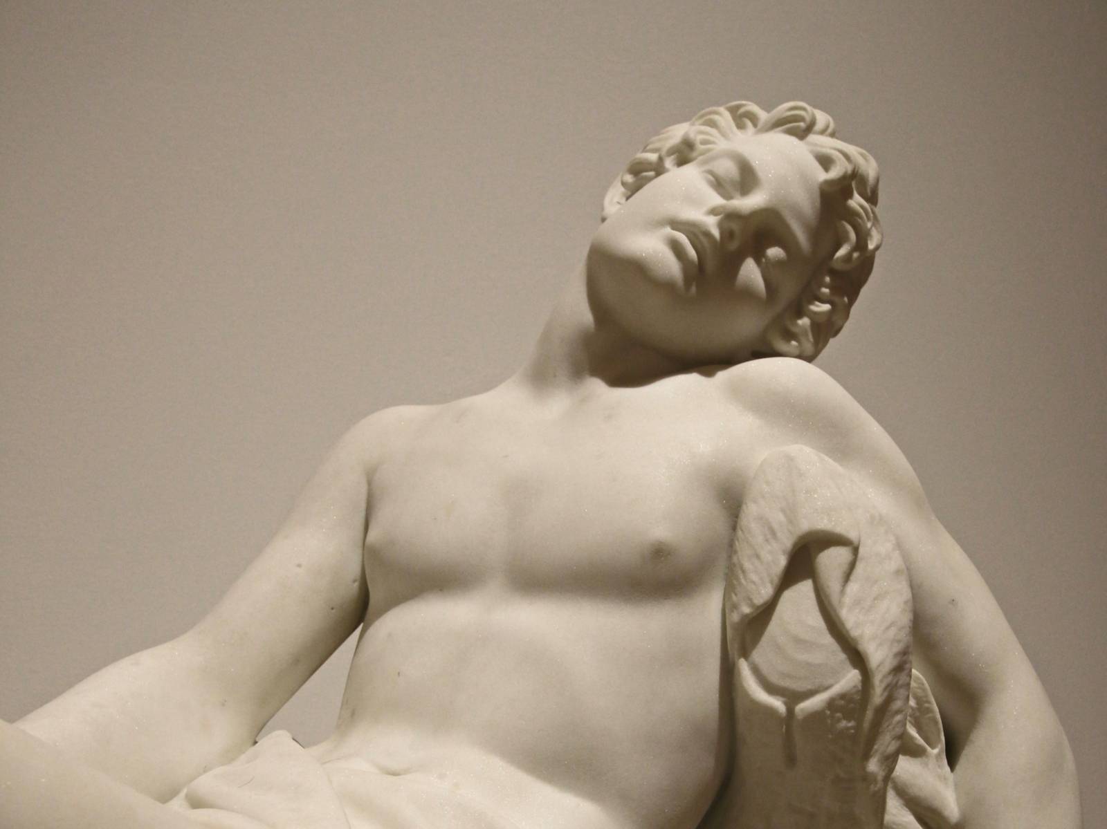 Bild einer männlichen Statue, die oberkörperfrei und mit geschlossenen Augen sitzt.