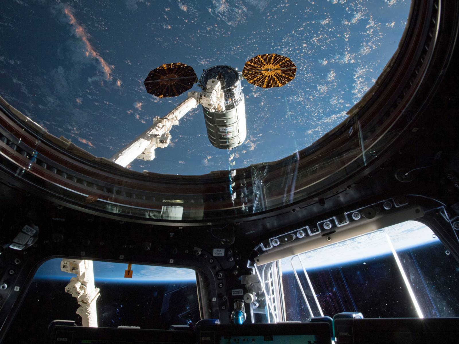 Blick durch ein Fenster in den Weltraum auf Teile einer Raumstation.