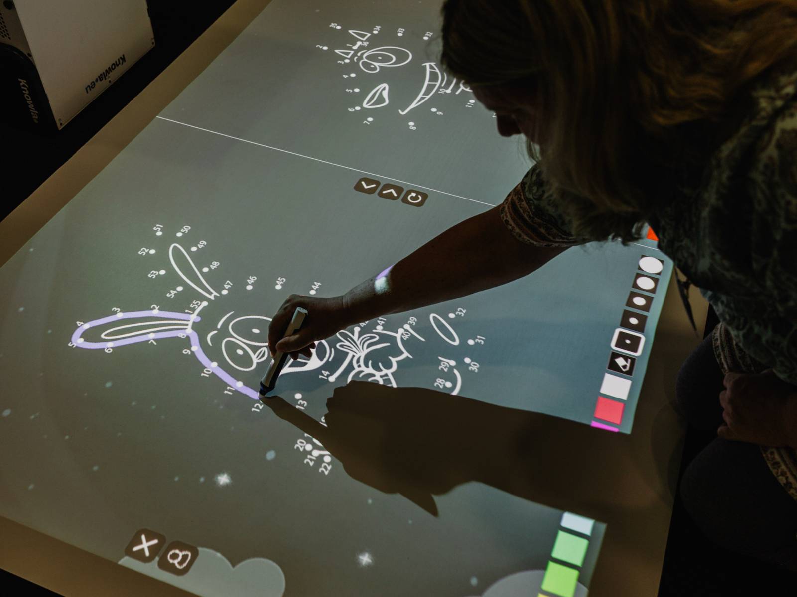 Eine Frau malt an einem interaktiven Bildschirm