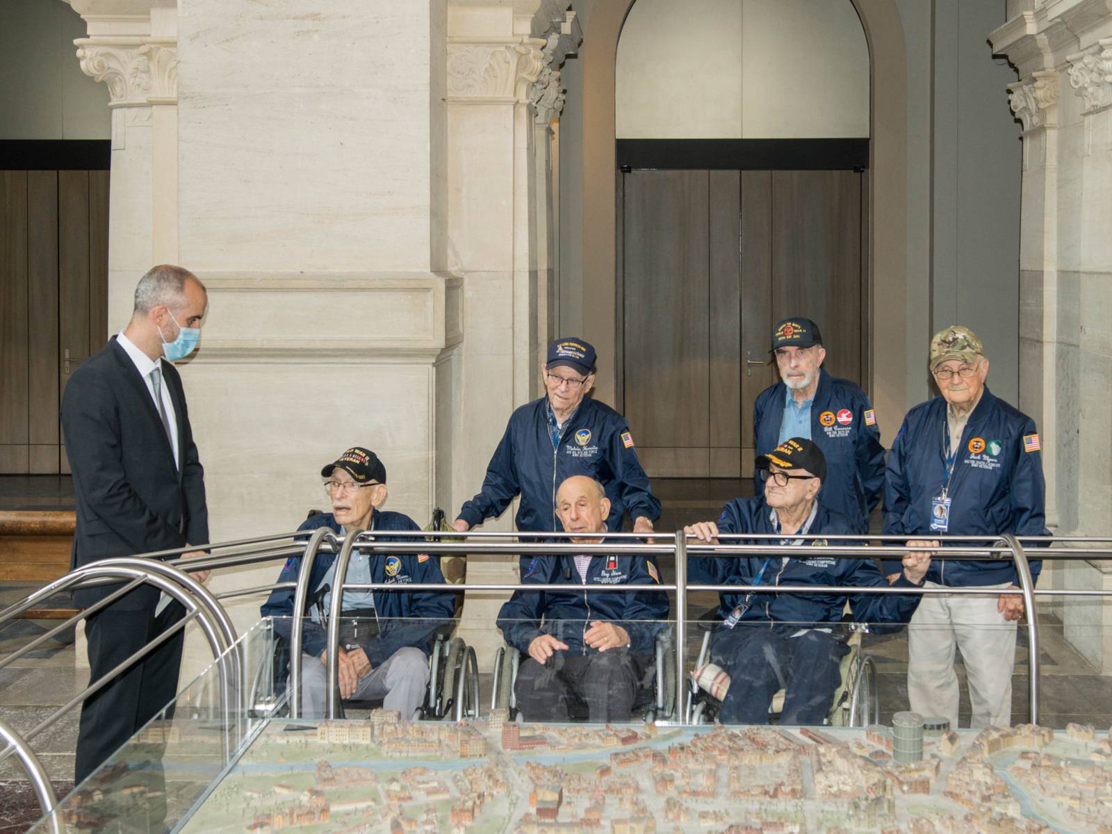 Oberbürgermeister Onay steht mit sechs US-Veteranen an einem Stadtmodell Hannovers.