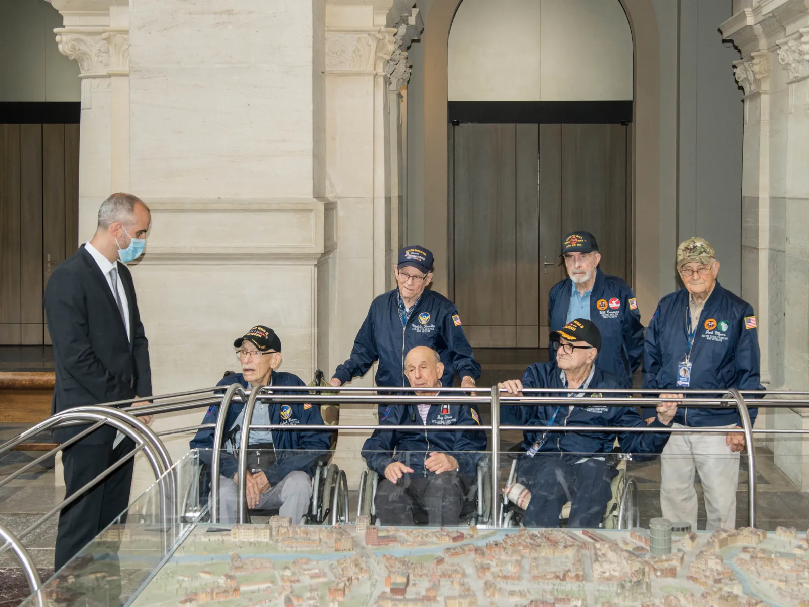 Oberbürgermeister Onay steht mit sechs US-Veteranen an einem Stadtmodell Hannovers.