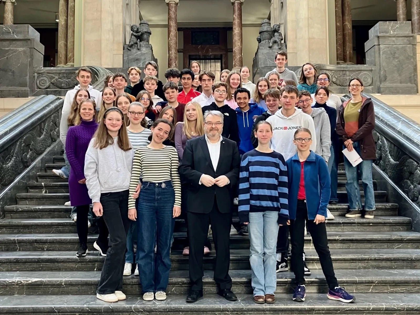Schüler*innen der Sophienschule Hannover und der Institution Jean-Paul II. aus Rouen stehen auf der Rathaustreppe des Neuen Rathauses Hannover, gemeinsam mit dem Bürgermeister der Landeshauptstadt Hannover Thomas Hermann.
