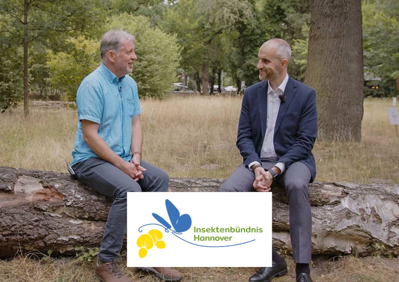 Koordinator Insektenbündnisses Ulrich Schmersow und OB Onay sitzen für ein Interview nebeneinander auf einem Baumstamm in der Culemannstraße.