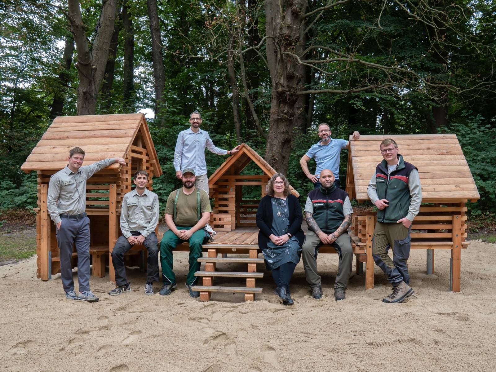 Acht Personen vor einem Spieldorf aus Holz.