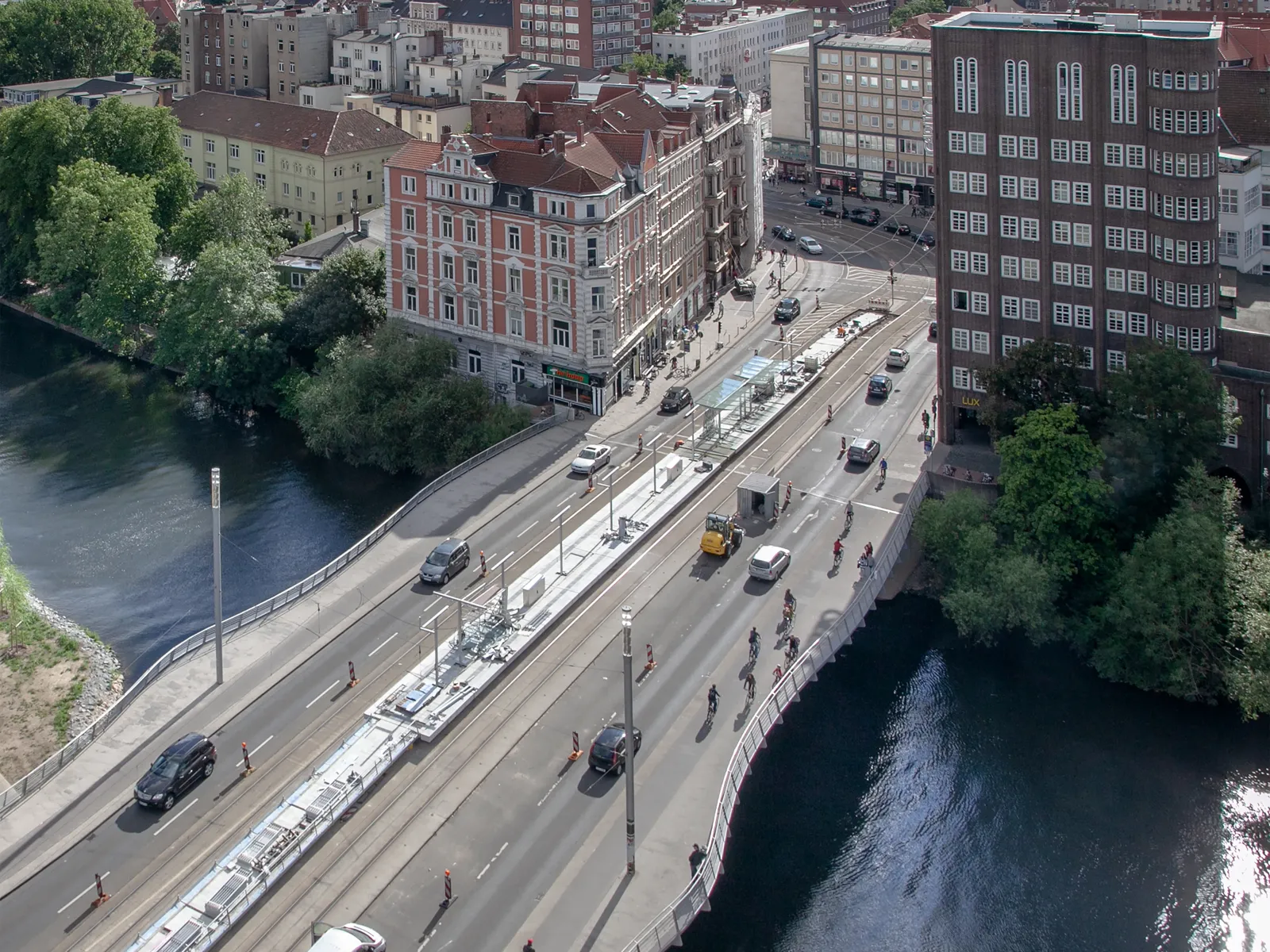 Bild von oben auf eine Br&uuml;cke mit Stra&szlig;e und Autos, darunter ein Fluss, im Hintergrund Geb&auml;ude.
