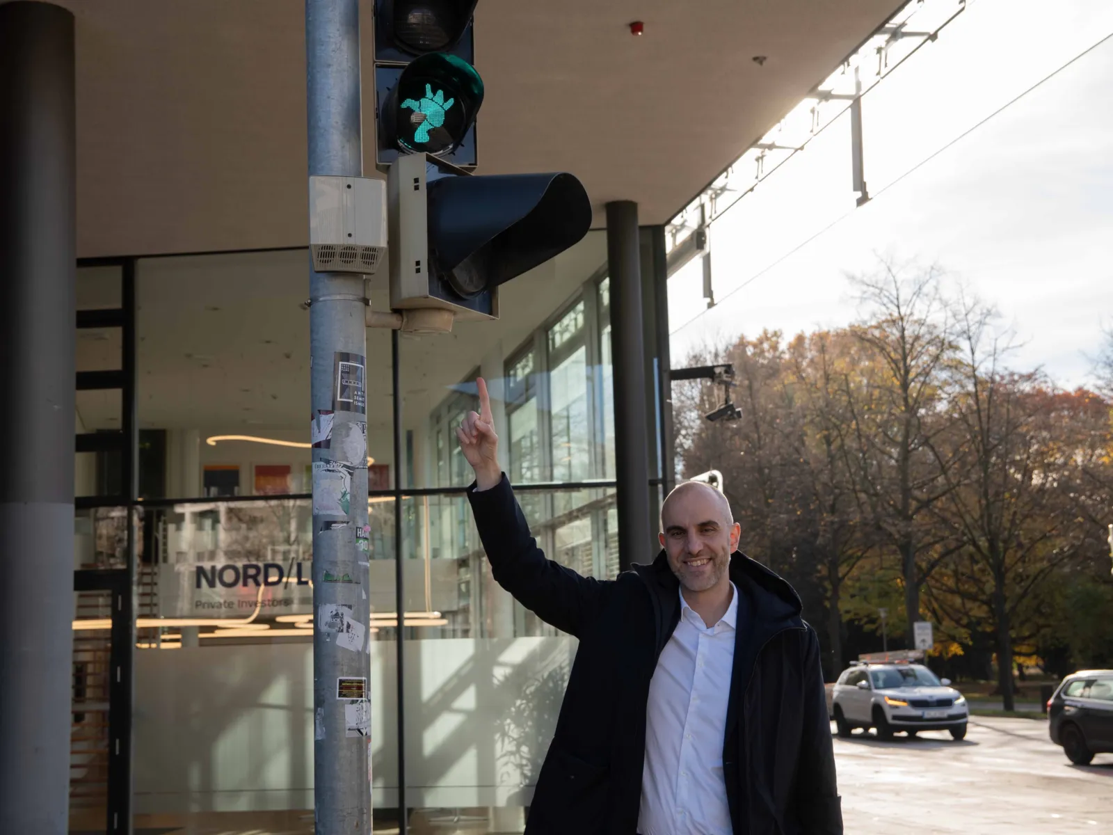 Ein Mann steht unter einem Ampelsignal und zeigt nach oben, dort ist ein gr&uuml;nes Licht in Form einer &uuml;ppigen Frauenfigur zu sehen.