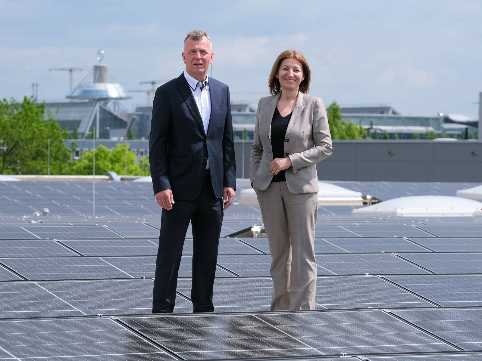Eine Frau und ein Mann stehen auf einem Dach mit Solarzellen.