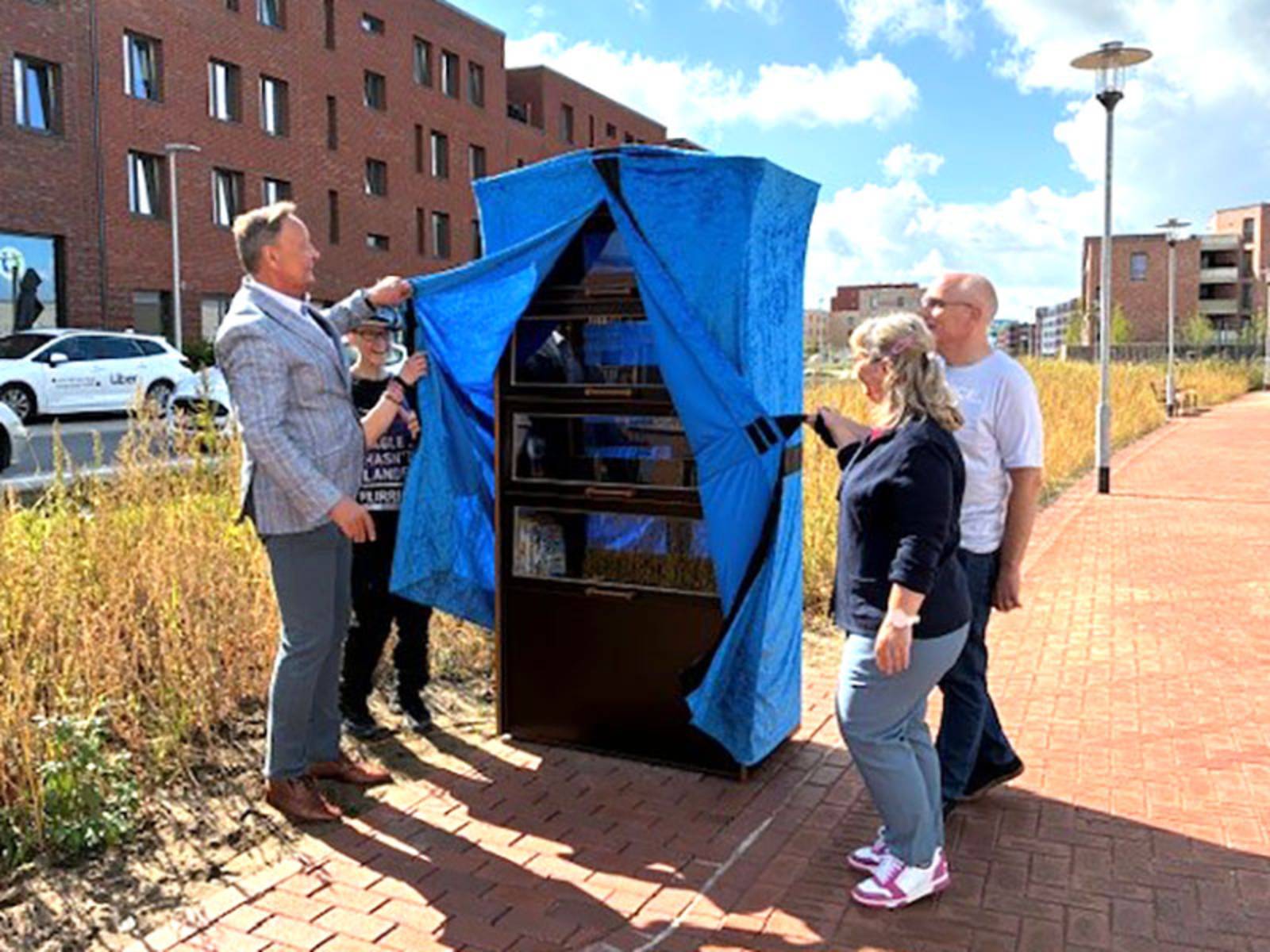 Bezirksbürgermeister Bernd Rödel enthüllt gemeinsam mit den Buchpaten den neuen Bücherschrank in Kronsberg.