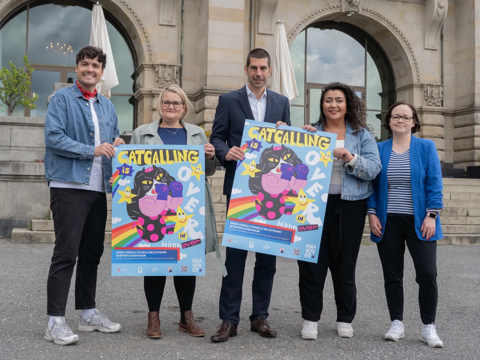 Fünf Personen halten zwei Poster in die Kamera mit dem Motiv einer illustrierten Katze mit Boxhandschuhen.