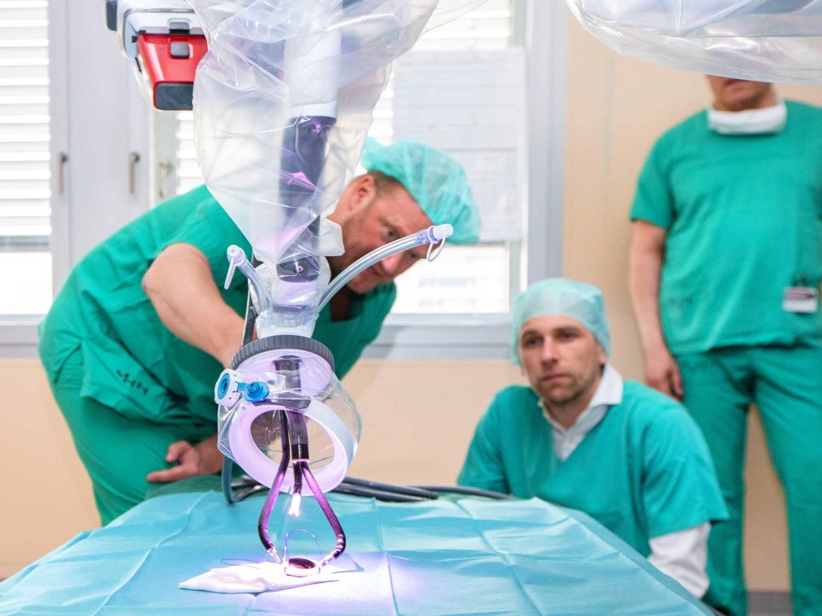 Drei Männer in medizinischer Schutzkleidung mit einem medizinischen Gerät.