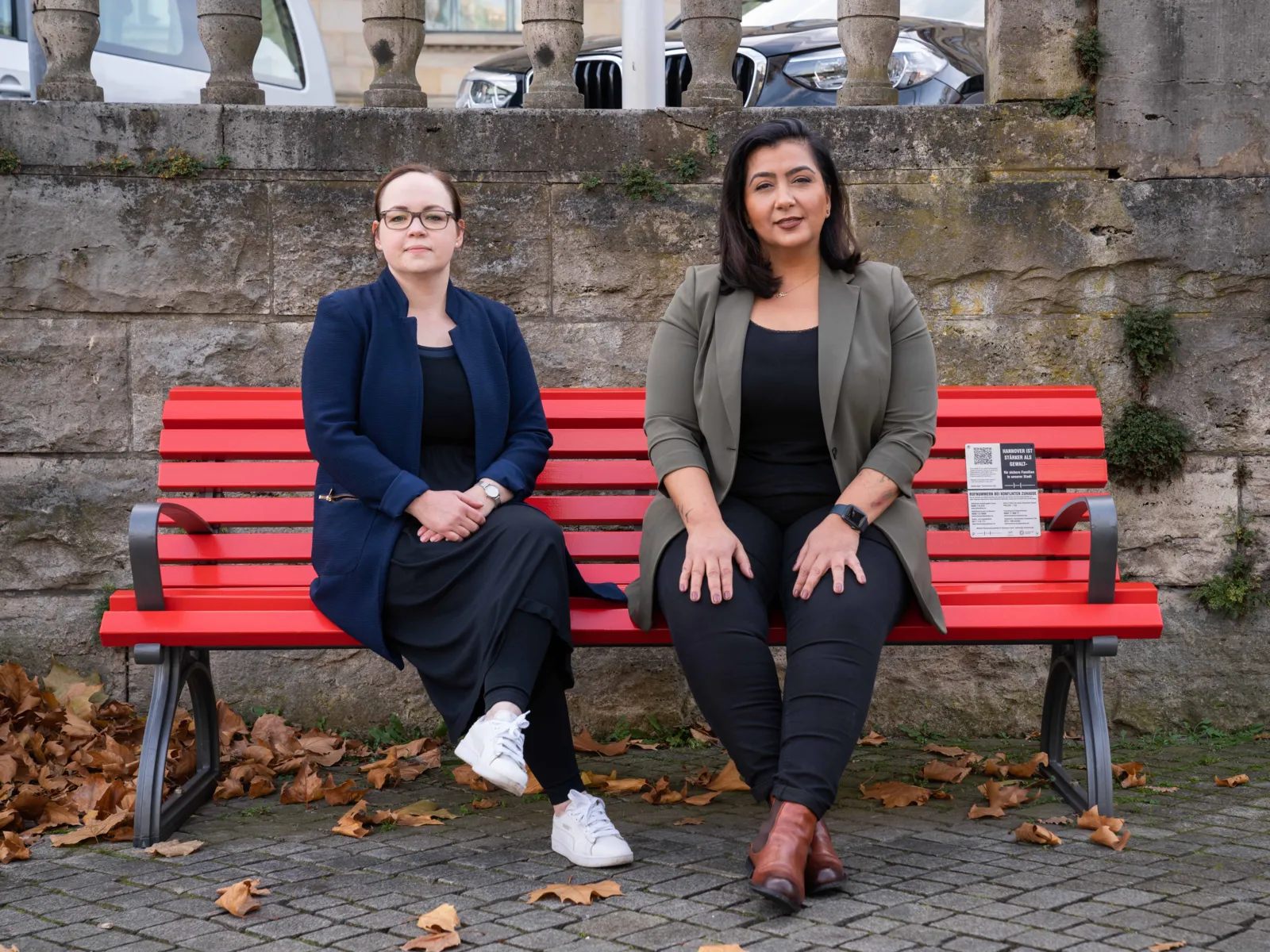 Zwei Frauen sitzen auf einer roten Bank