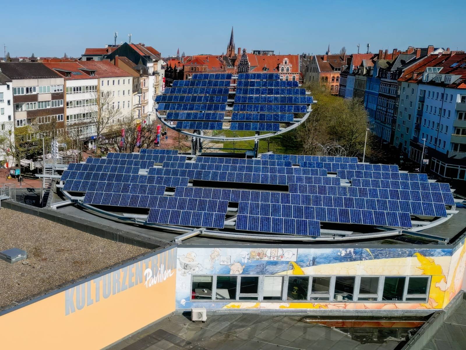 Ein Gebäude von oben, auf dessen Dach zwei Solarfächen rund angeordnet sind.