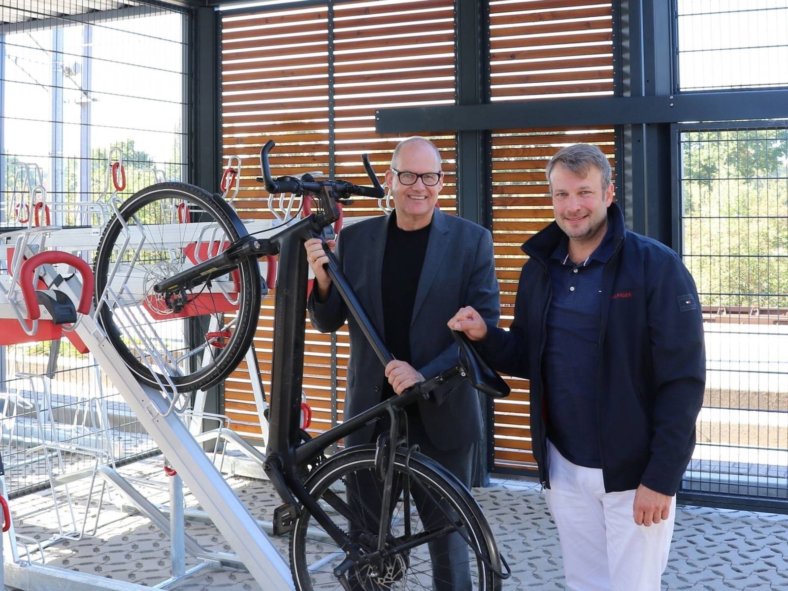Zwei Politiker pr&auml;sentieren das Abstellen eines E-Bikes an einem Fahrradst&auml;nder.
