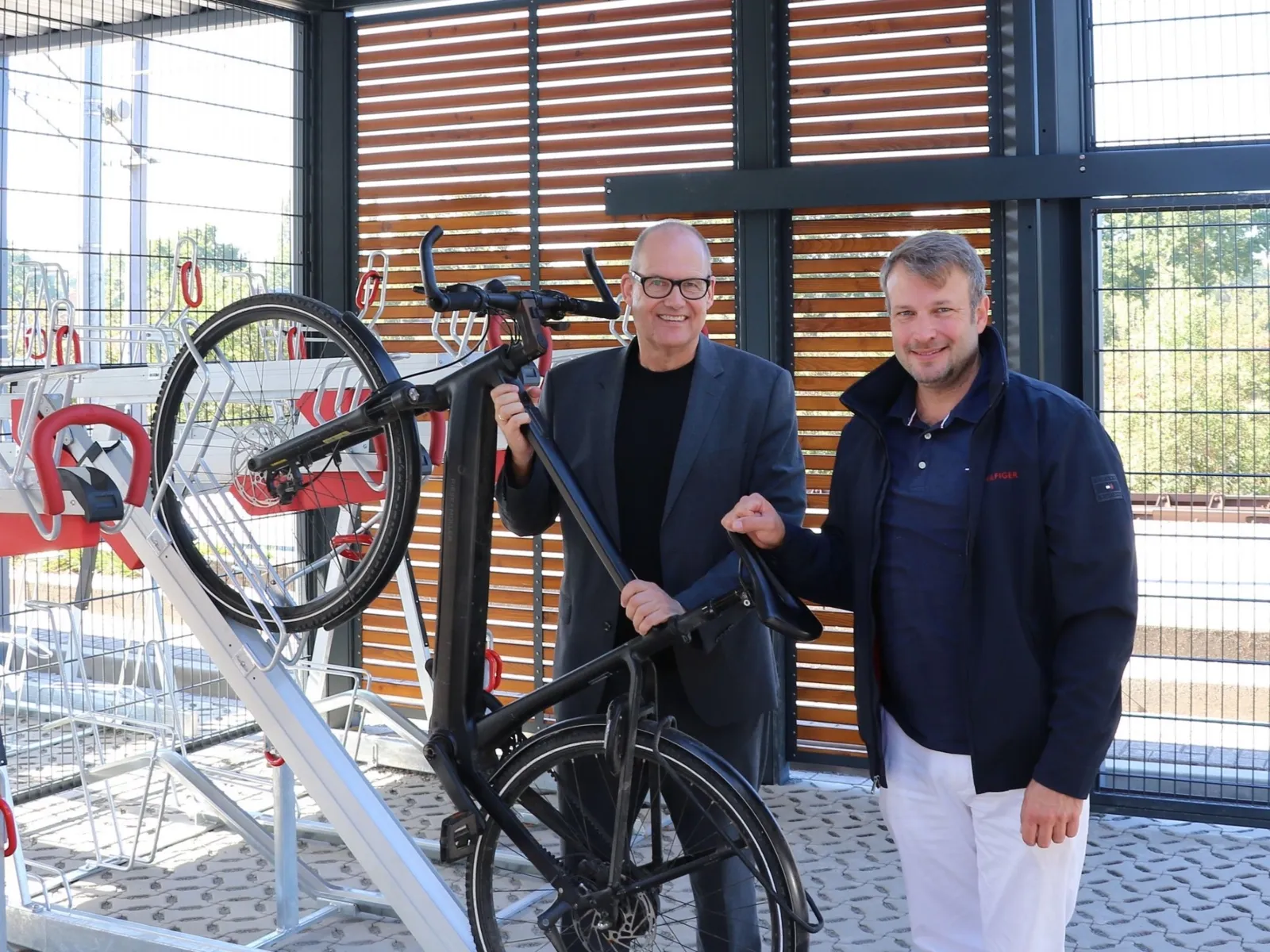 Zwei Politiker pr&auml;sentieren das Abstellen eines E-Bikes an einem Fahrradst&auml;nder.