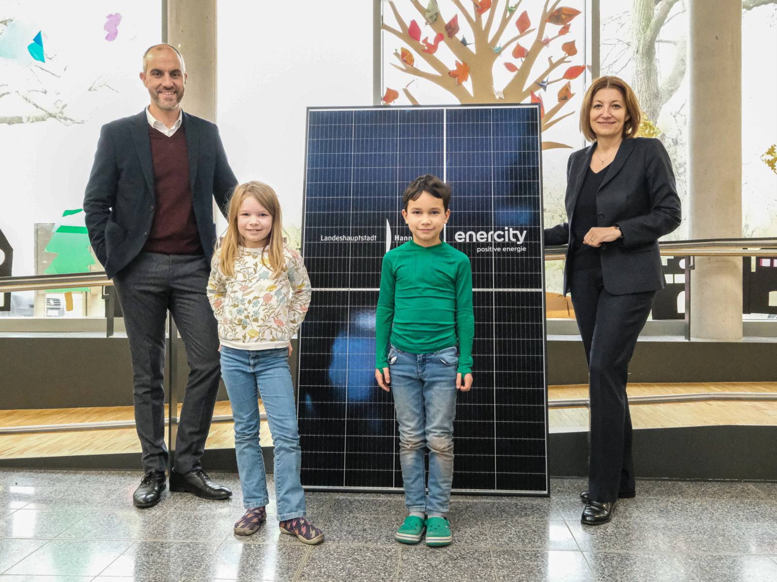 Zwei Erwachsene und zwei Kinder vor einer Solar-Panele.