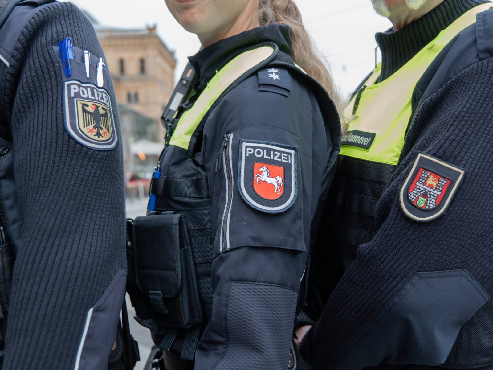 Die Patches von Bundespolizei, Landespolizei Niedersachsen und städtischem Ordnungsdienst Hannover werden in die Kamera gehalten.
