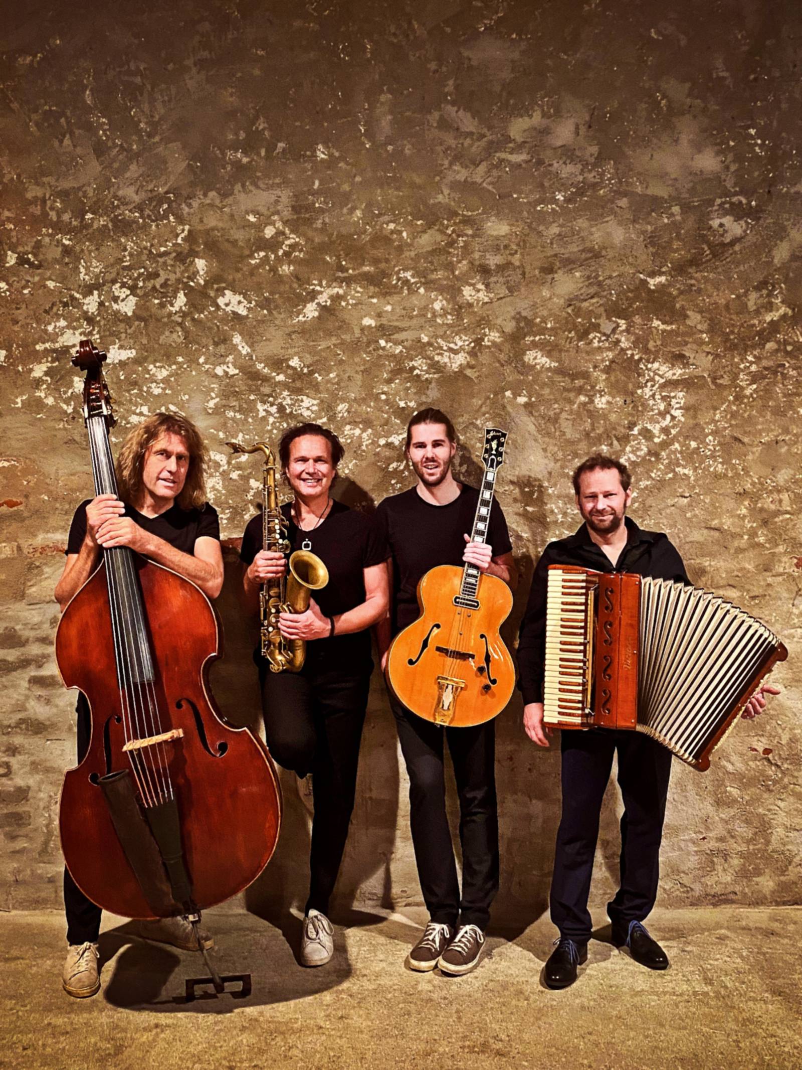 Vier Musiker stehen mit ihren Instrumenten nebeneinander.