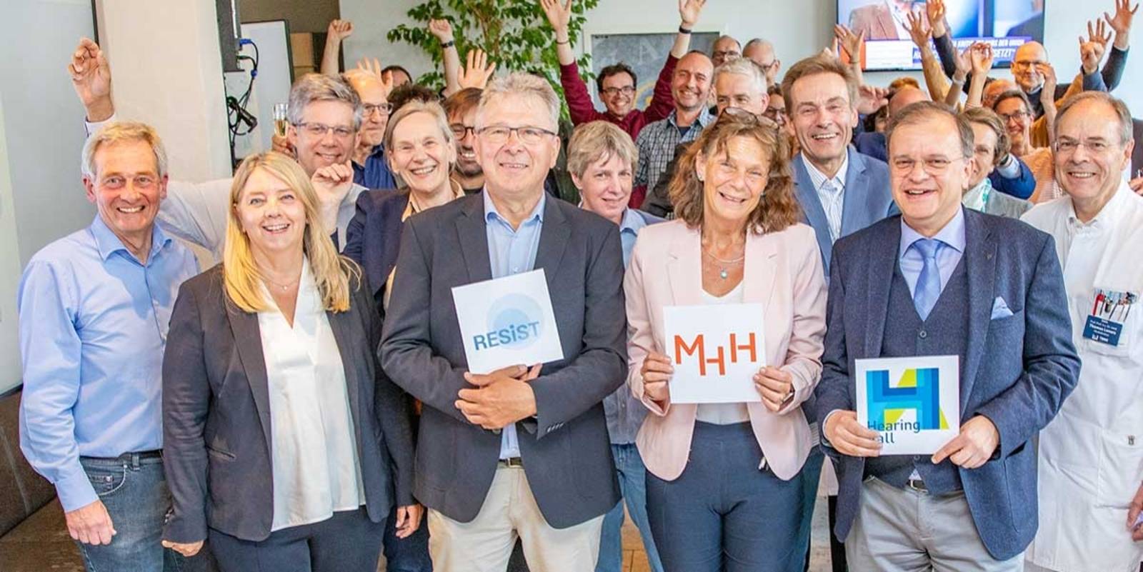 Menschengruppe, drei halten Tafeln mit Logos in den H&auml;nden.