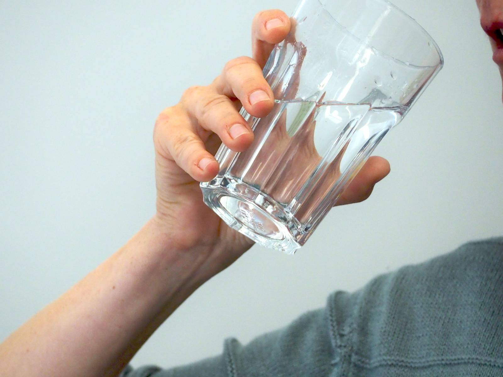 Eine Frau trinkt Wasser aus einem großen Glas.