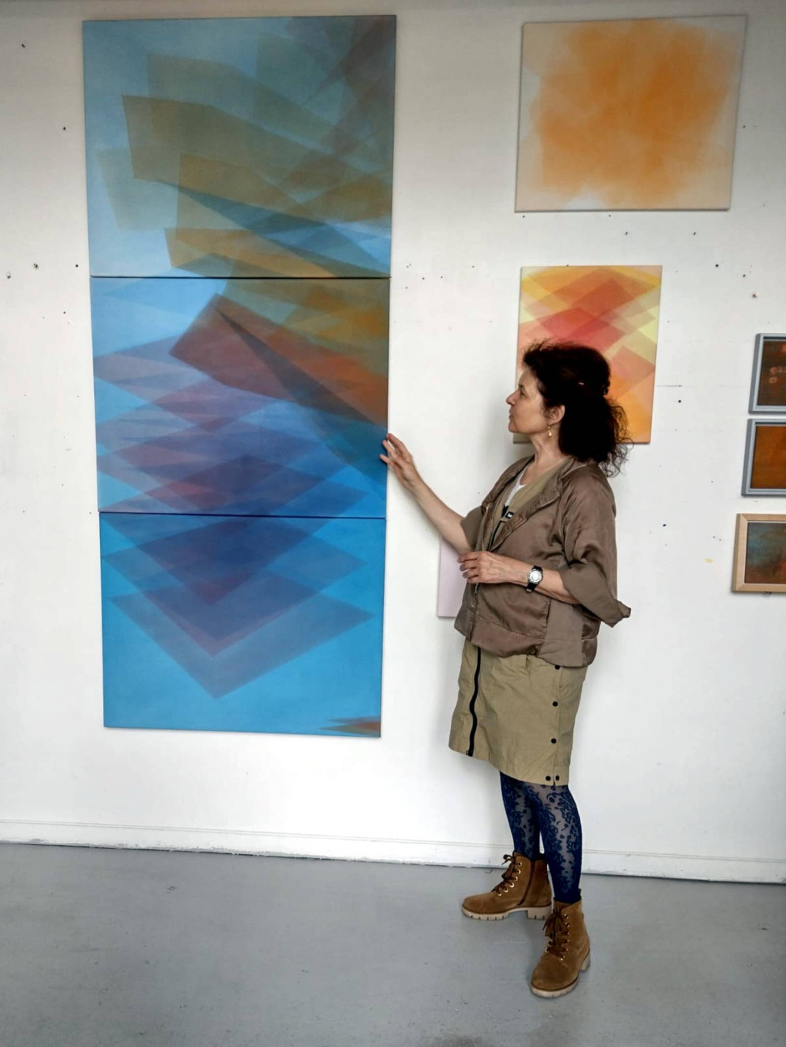 Eine Künstlerin zeigt Bilder an der Wand ihres Ateliers.