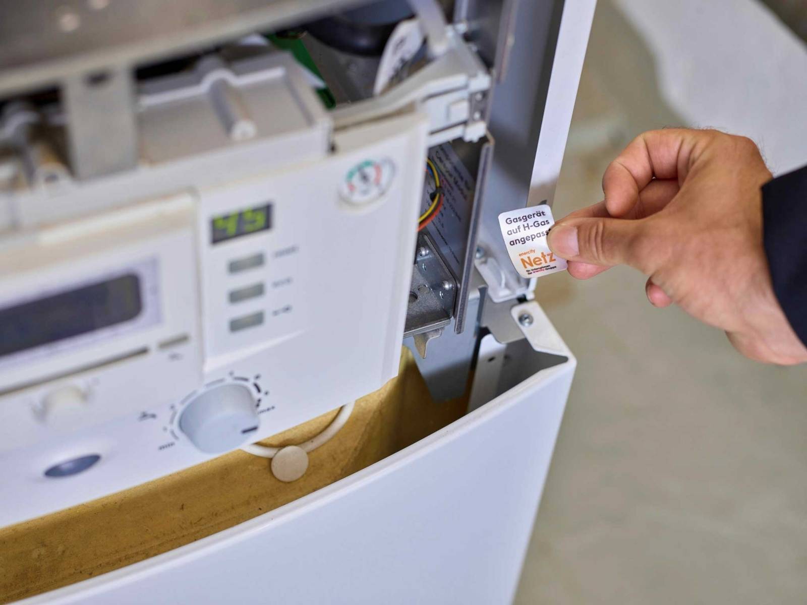 Hand hält Siegel mit der Aufschrift "Gasgerät auf H-Gas angepasst".