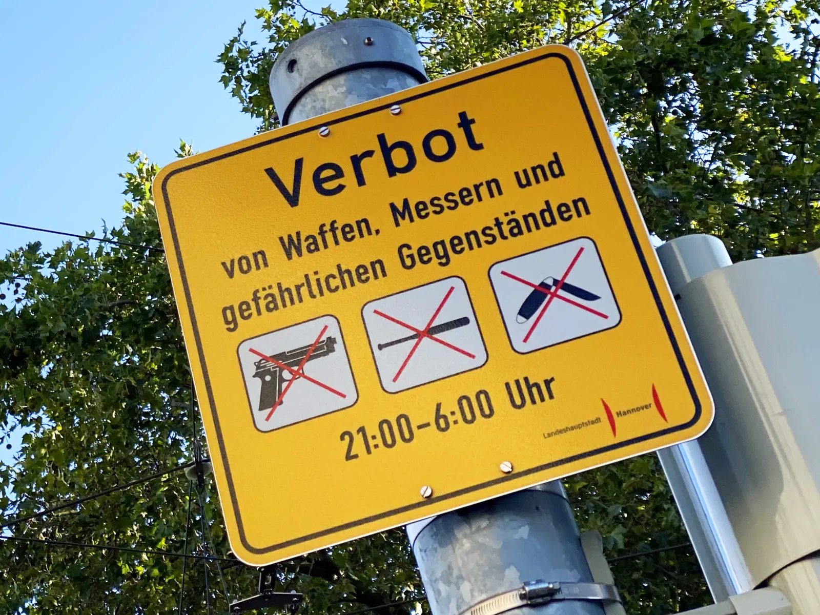 Ein Schild. Darauf steht "Verbot von Waffen, Messern und gefährlichen Gegenständen".