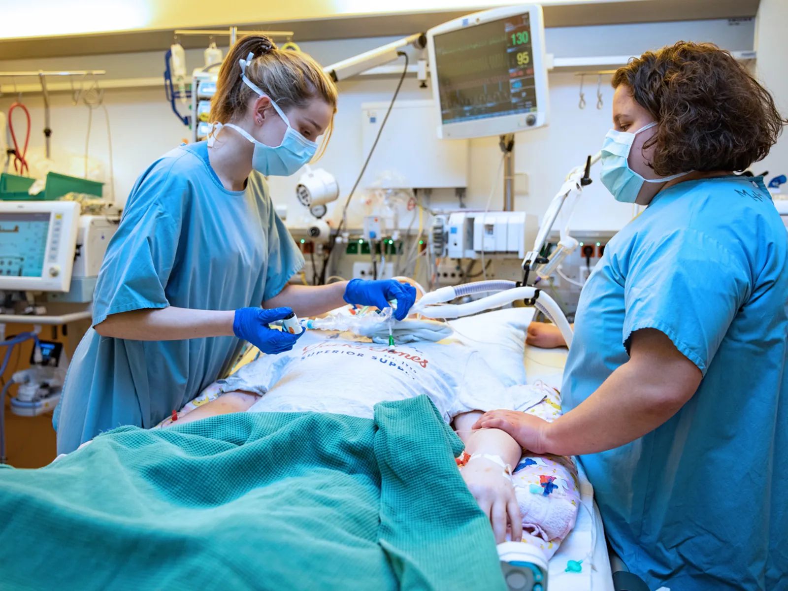 Zwei Pflegekräfte auf einer Intensivstation am Bett eines Patienten.