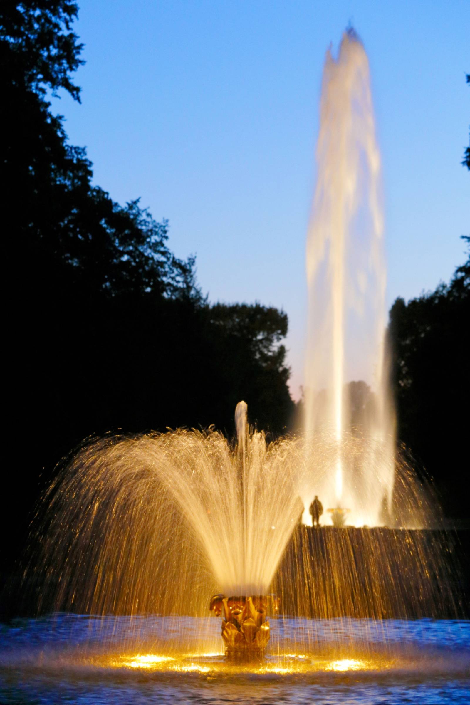 Beleuchteter Springbrunnen und Fontäne im abendlichen Großen Garten