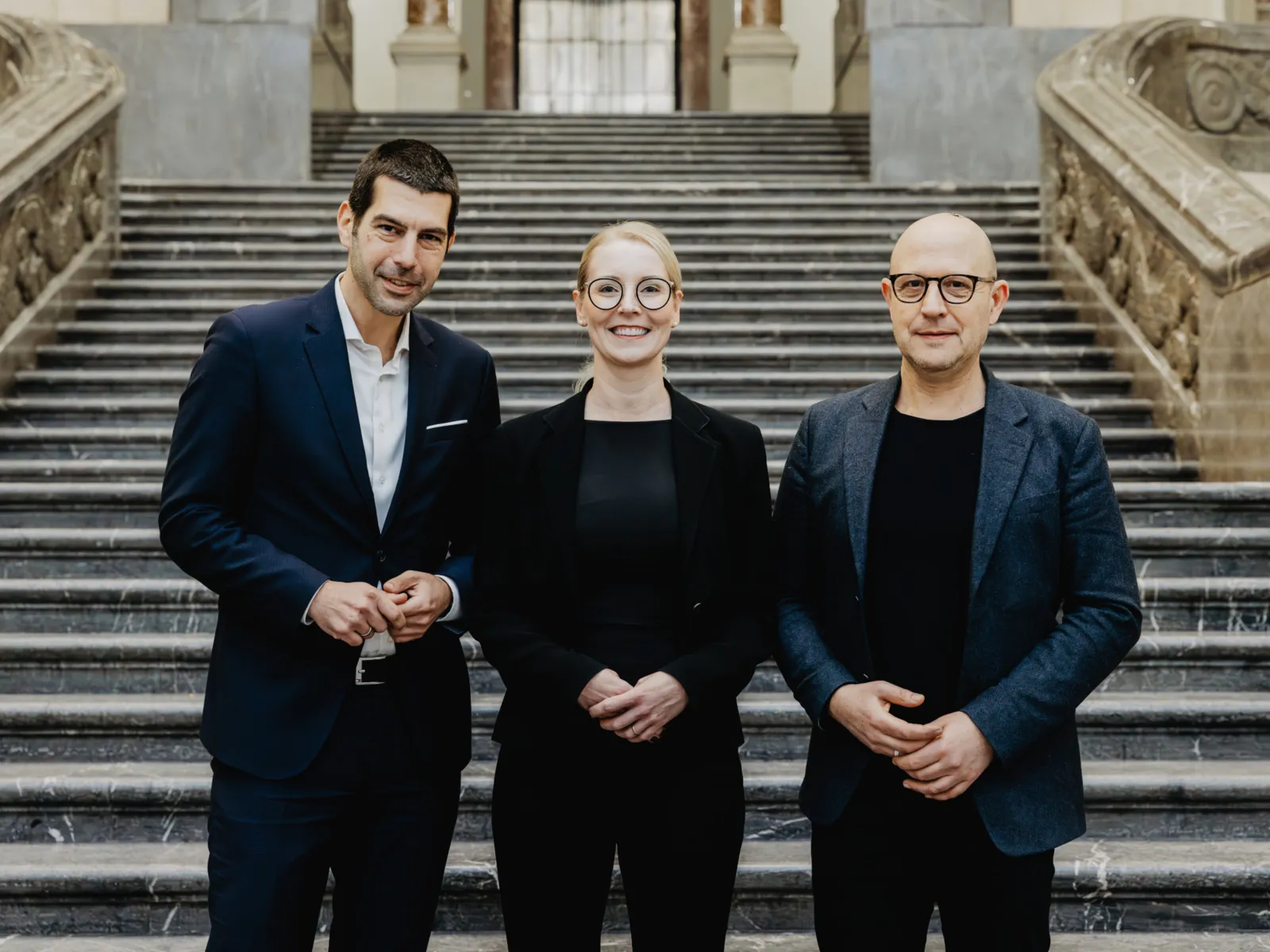 Drei Personen vor einer großen Treppe