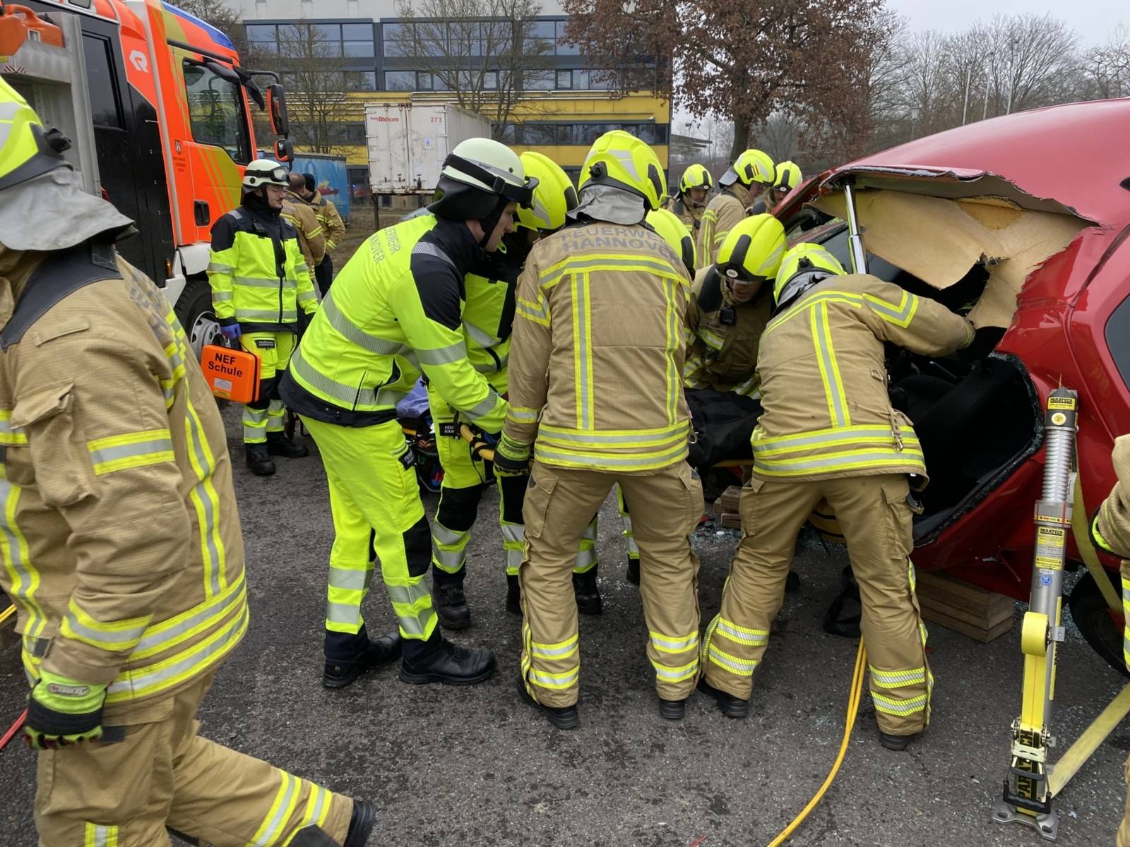 Auszubildende in der Abschlussübung, die aus einem abgestützten Auto eine Simulationspuppe retten