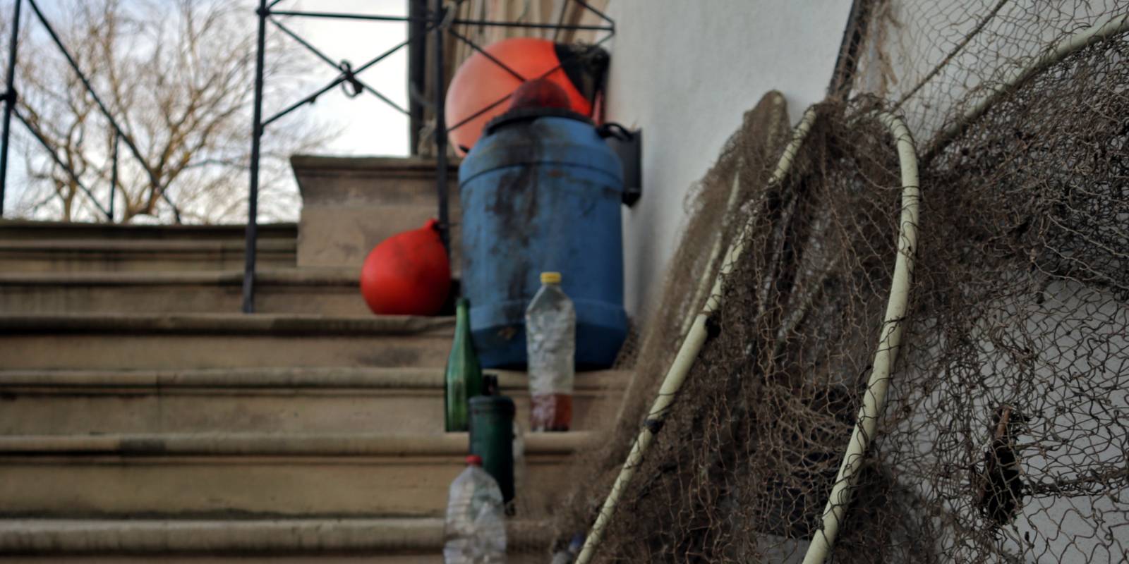 Verschiedene, weggeworfene Gegenstände stehen auf den Treppenstufen von Schloss Landestrost, darunter Netze, Bojen, Trinkflaschen und eine Plastiktonne.