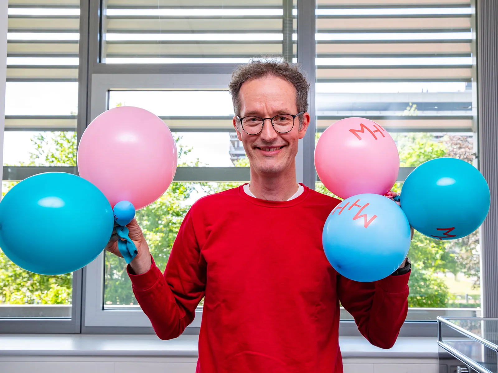 Ein Mann hält Luftballons in den Händen.