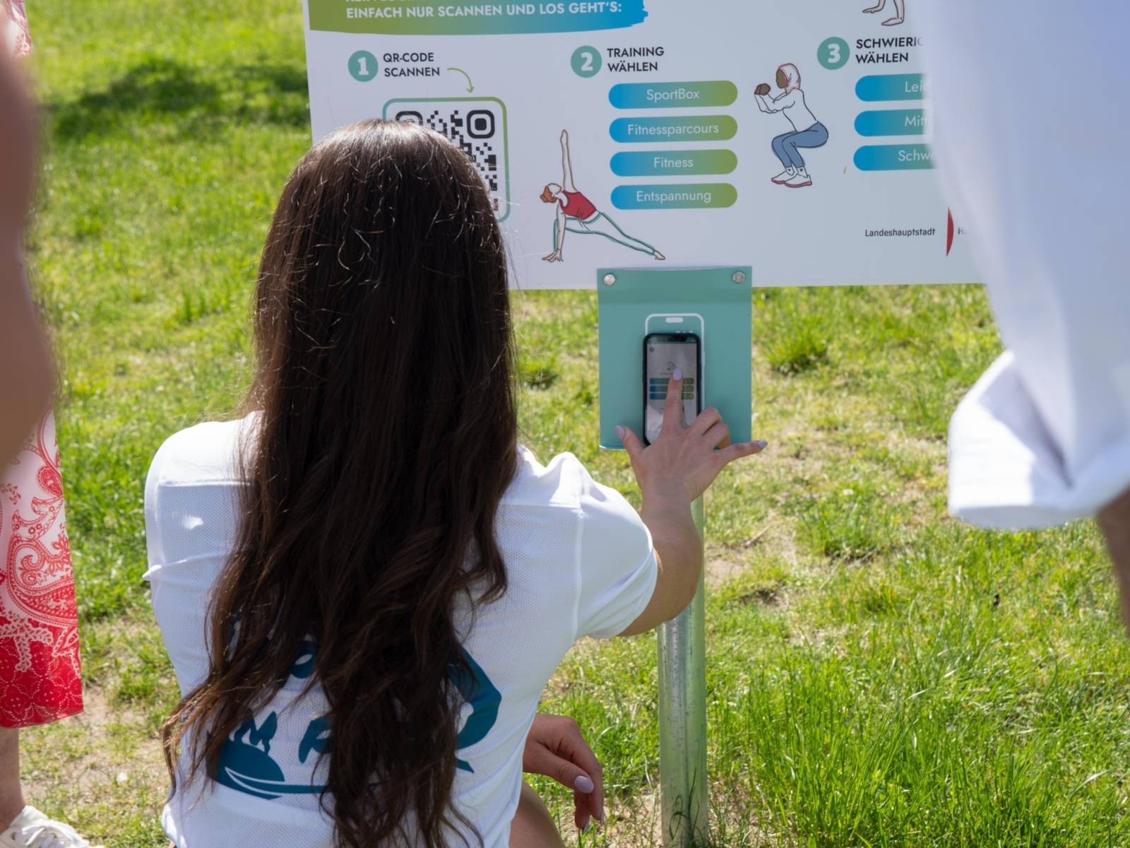 Eine Person, die im Freien einen QR-Code scannt.