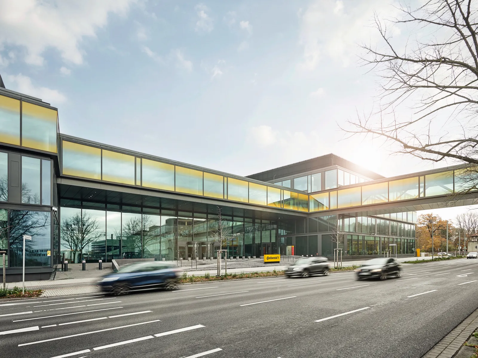 Modernes B&uuml;rogeb&auml;ude mit Stra&szlig;e mit vorbeifahrenden Autos davor.