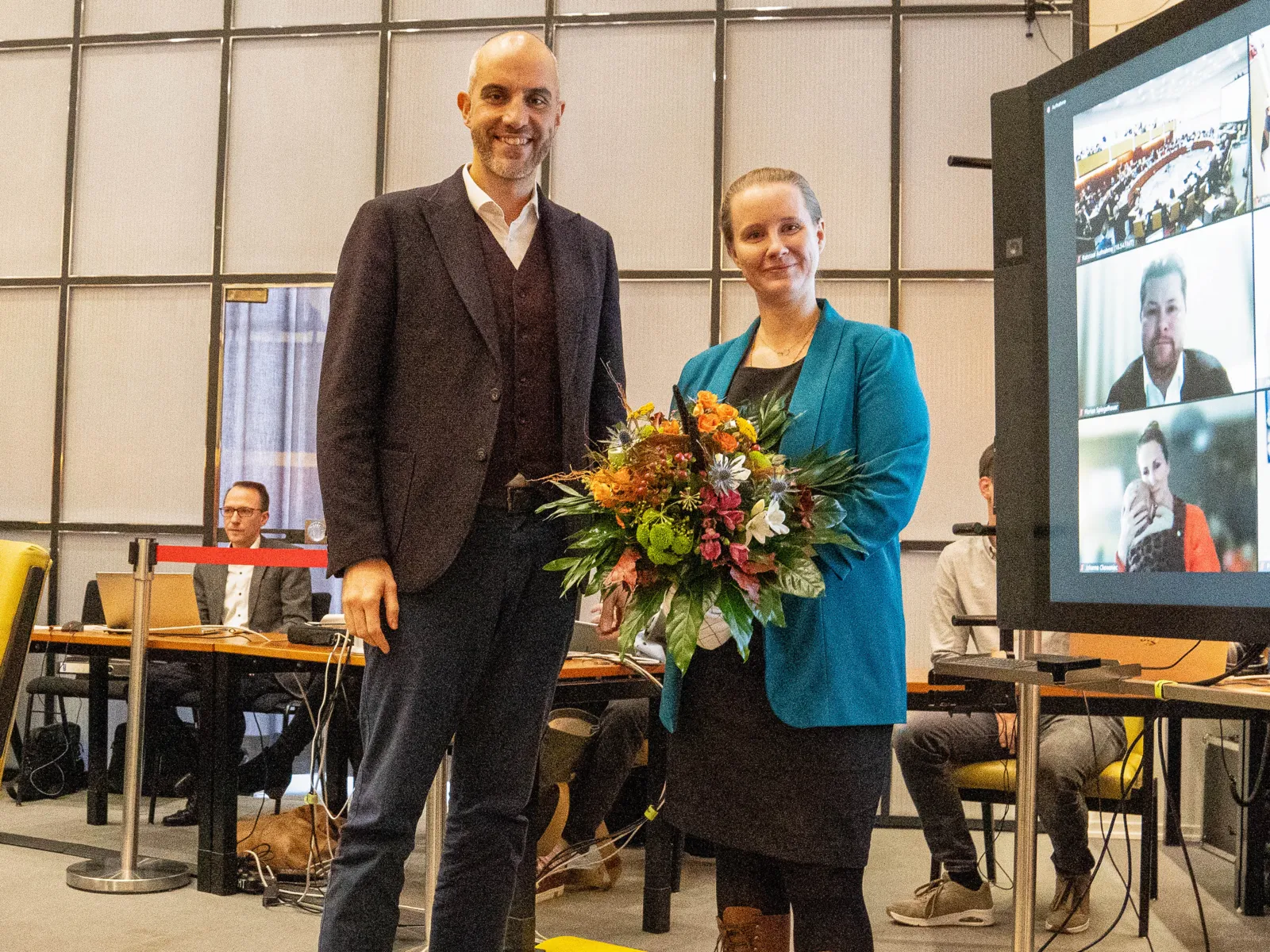 Zwei Personen mit einem Blumenstrauss in einem Saal.