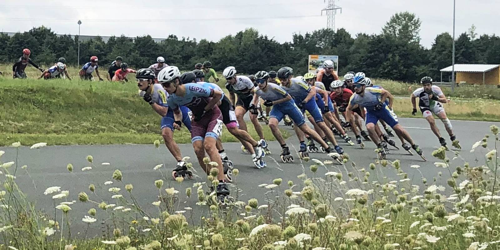 Inline-Skater fahren auf einer Stra&szlig;e hintereinander durch eine Kurve.