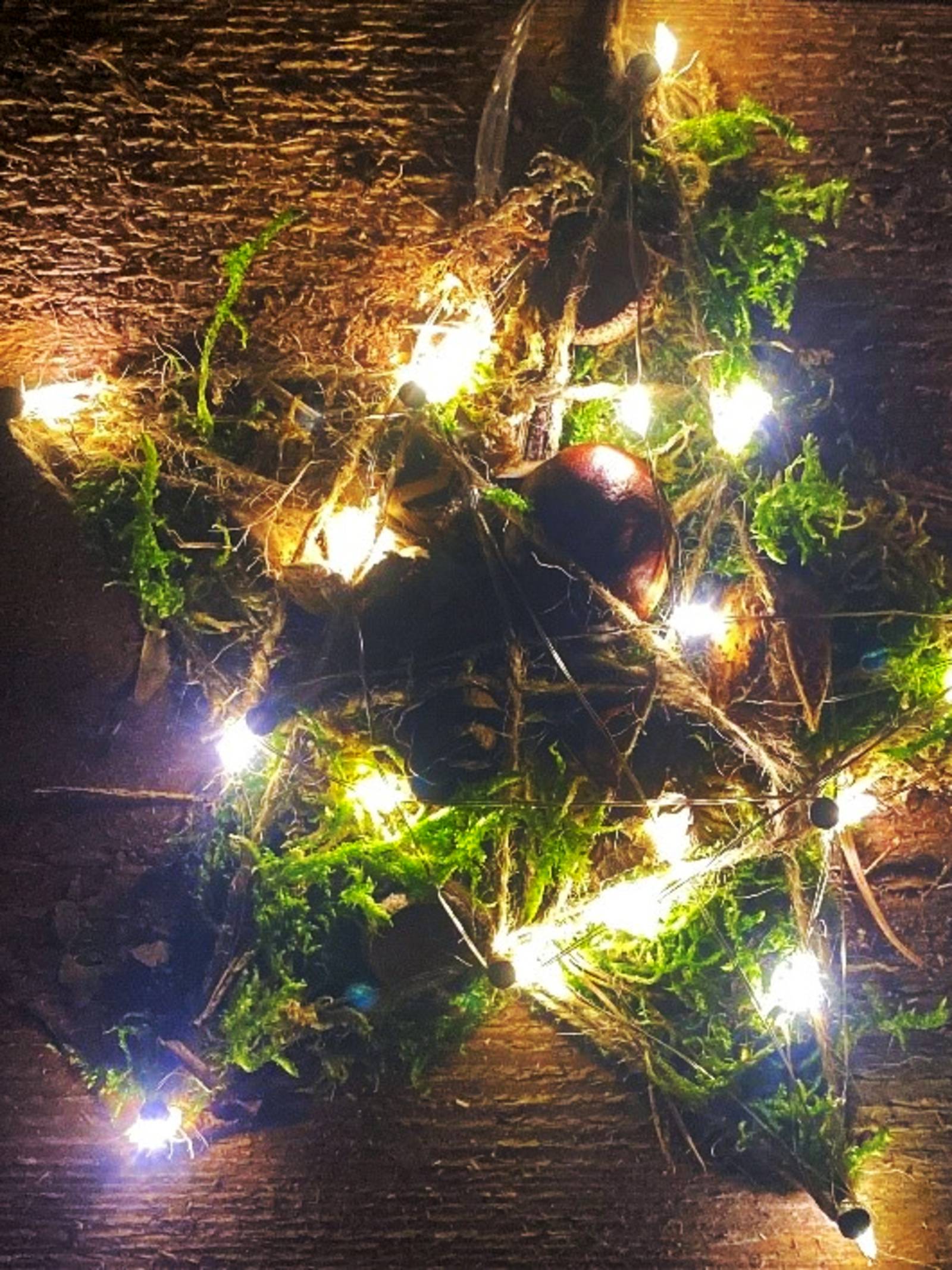 Ein gebastelter, leuchtender Stern liegt auf einem Tisch.