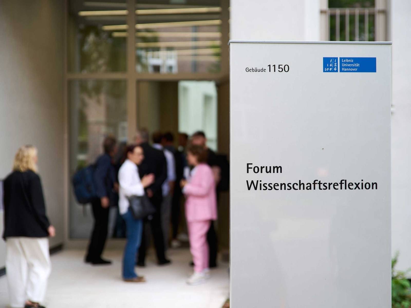 Menschen hinter Schild mit der Aufschrift "Forum Wissenschaftreflexion"