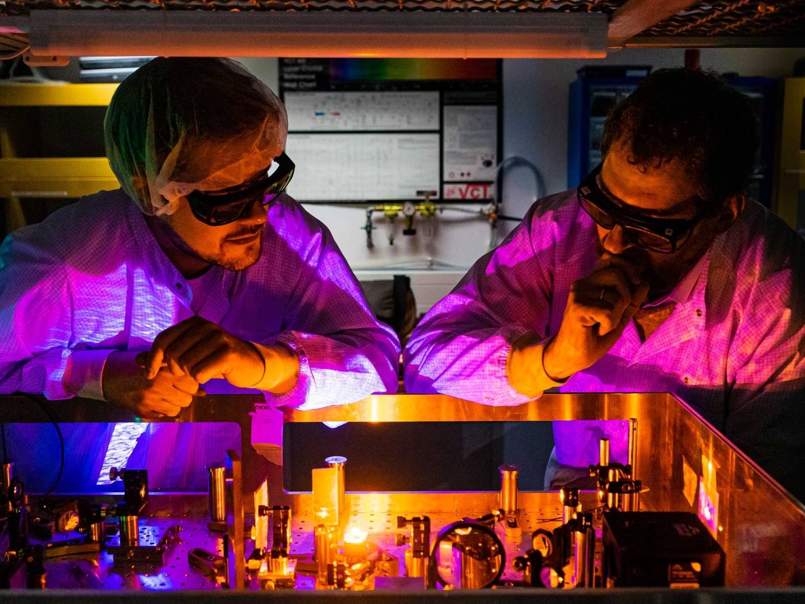 Zwei Menschen mit Schutzbrillen an einer optischen Apparatur.