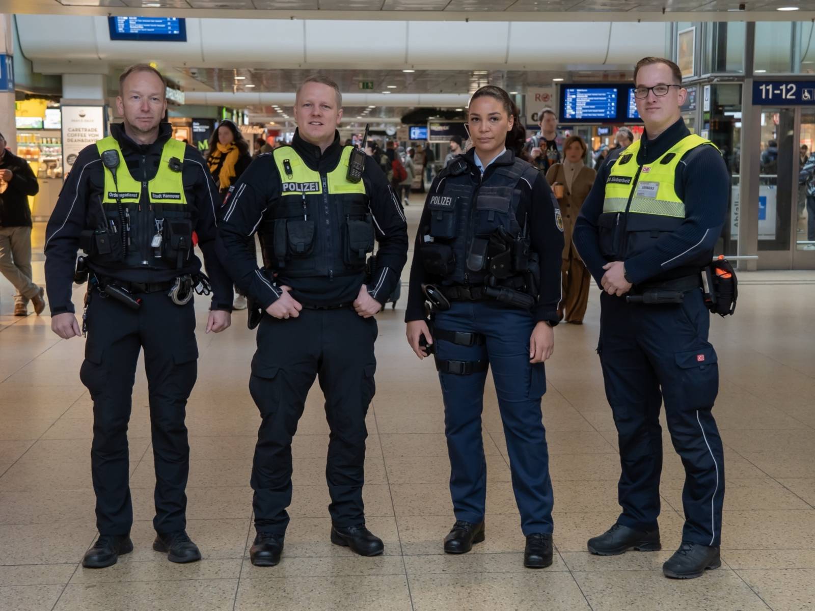 Vier Personen in Uniform stehen in einer Reihe und schauen in die Kamera.