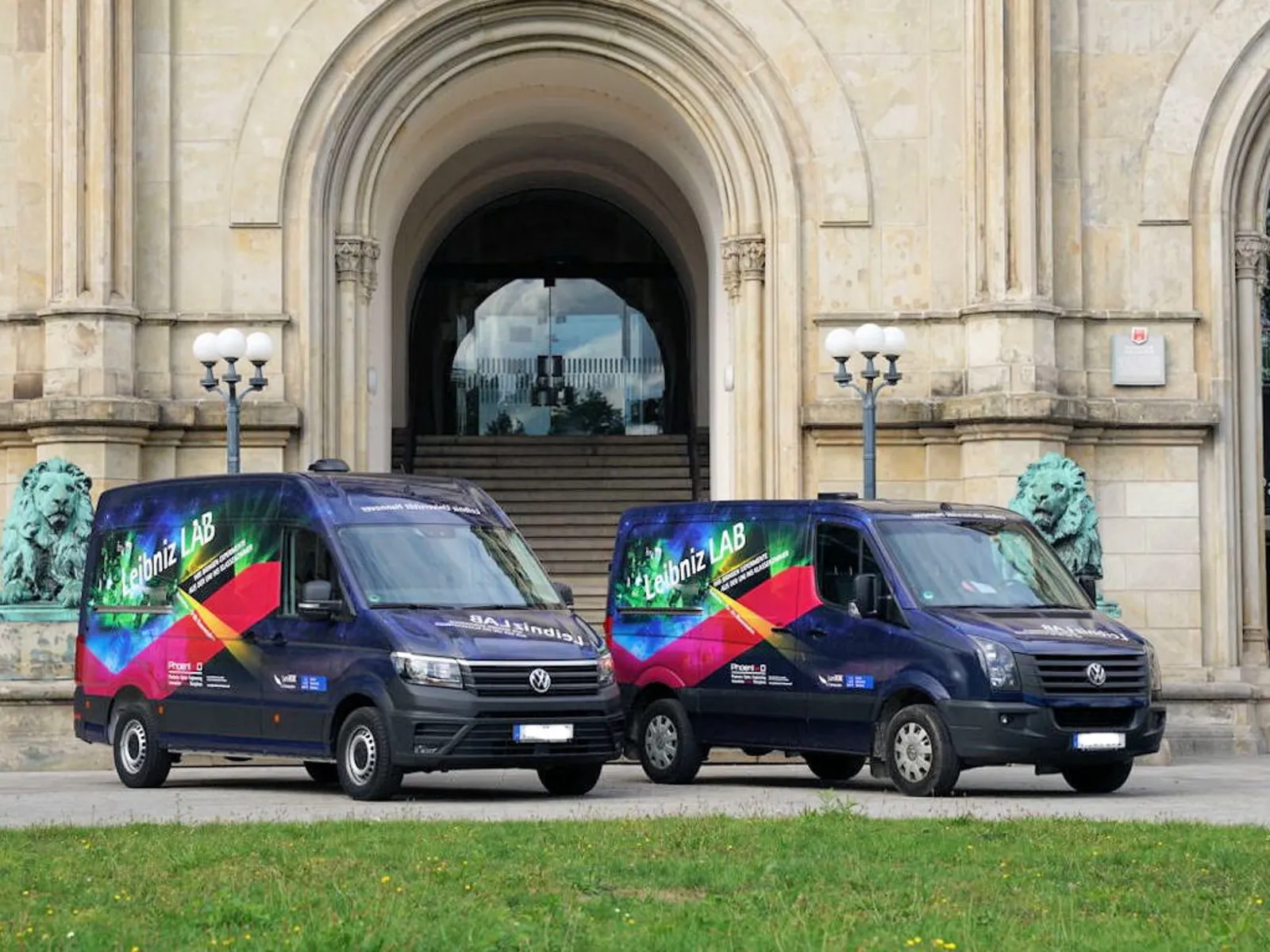 Zwei Transporter mit der Aufschrift "LeibnizLAB" vor dem Portal eines historischen Gebäudes.
