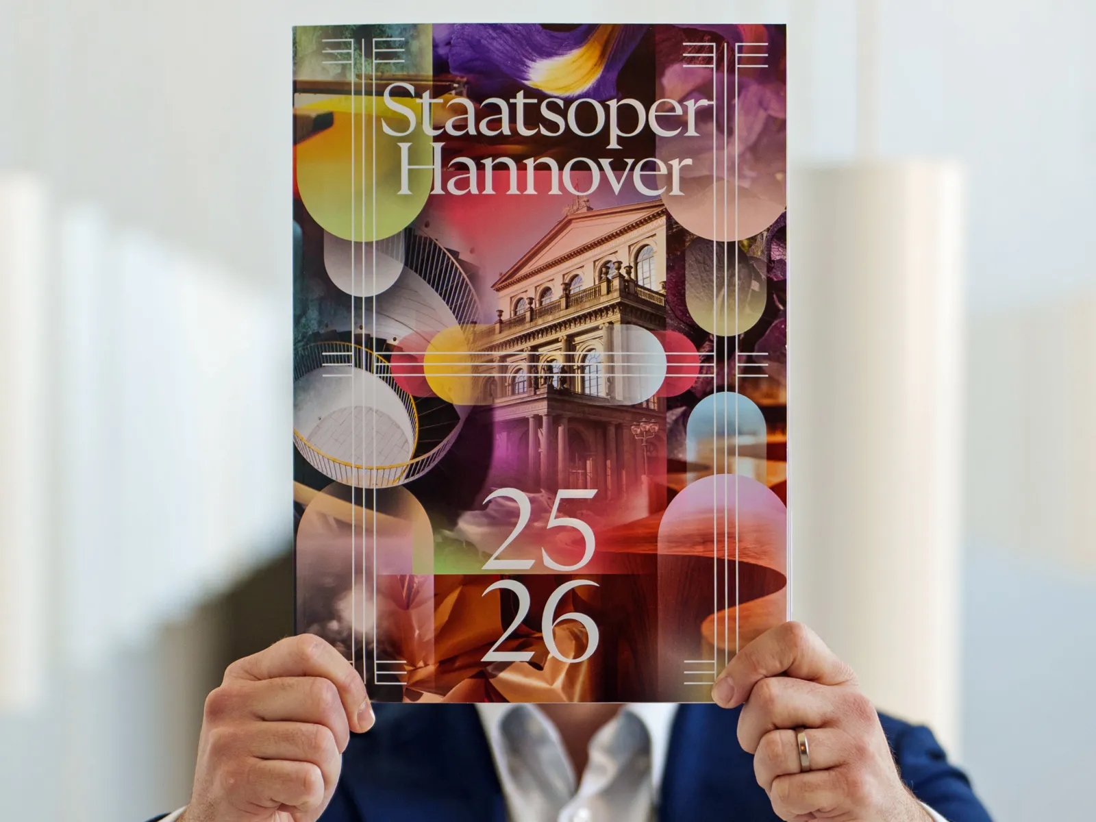Mann hält ein Programmheft in die Kamera.